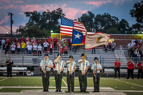 ROTC holding a flag in the middle of a football field.